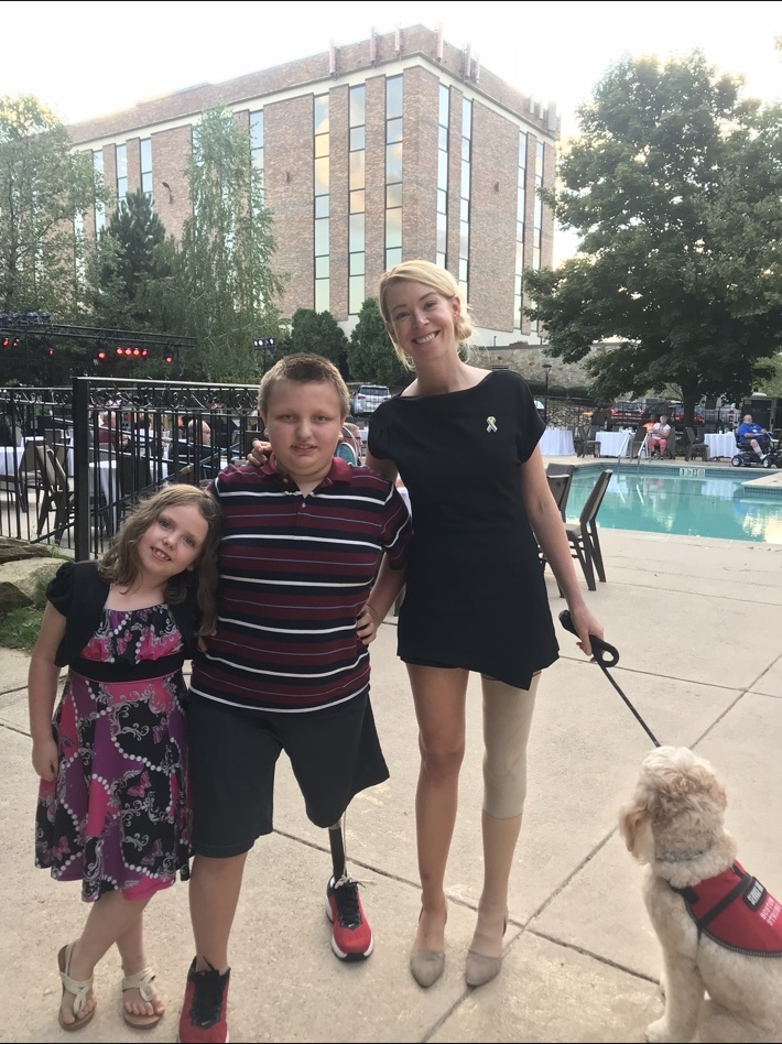 Adrianne Haslet with two children and a service dog at a community event