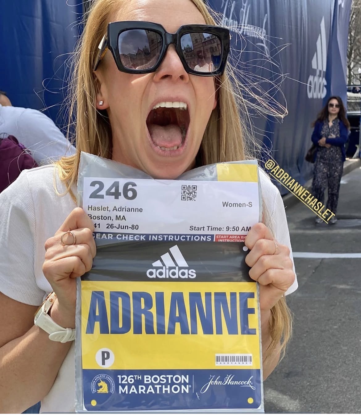 Adrianne Haslet joyfully holding her Boston Marathon race bib